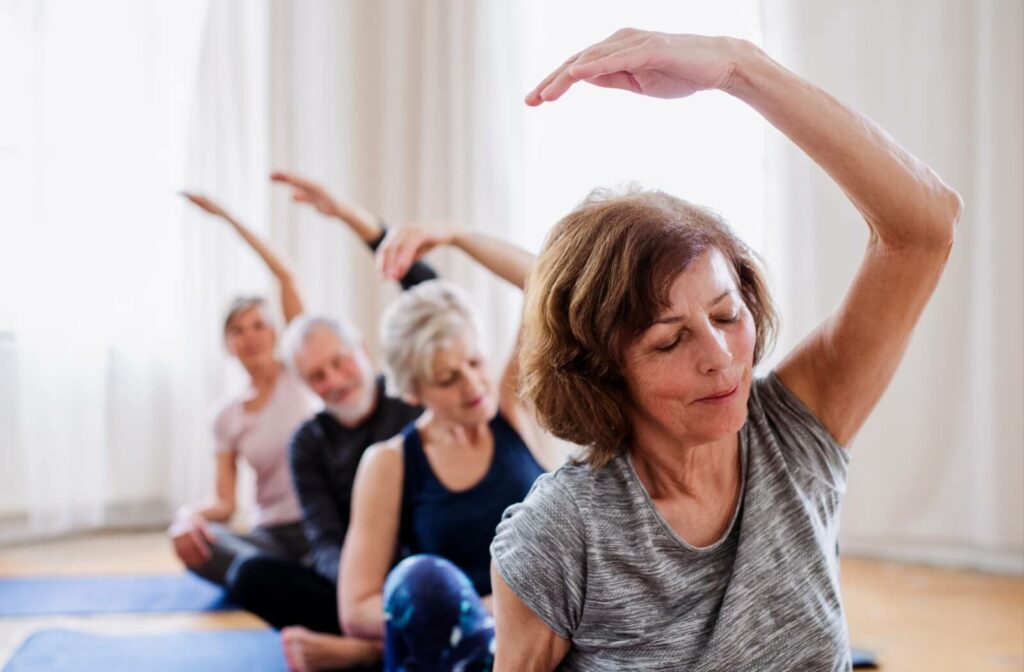 Older adults participate in an indoor group fitness class to help their flexibility.
