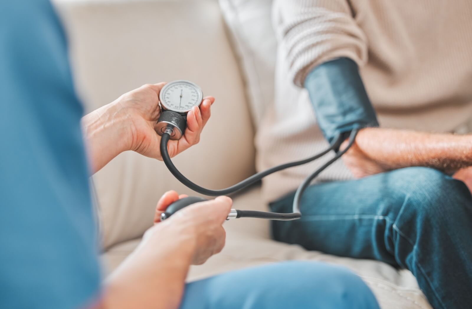 A nurse watches the needle on a blood pressure cuff to measure an older adult's blood pressure as part of health monitoring