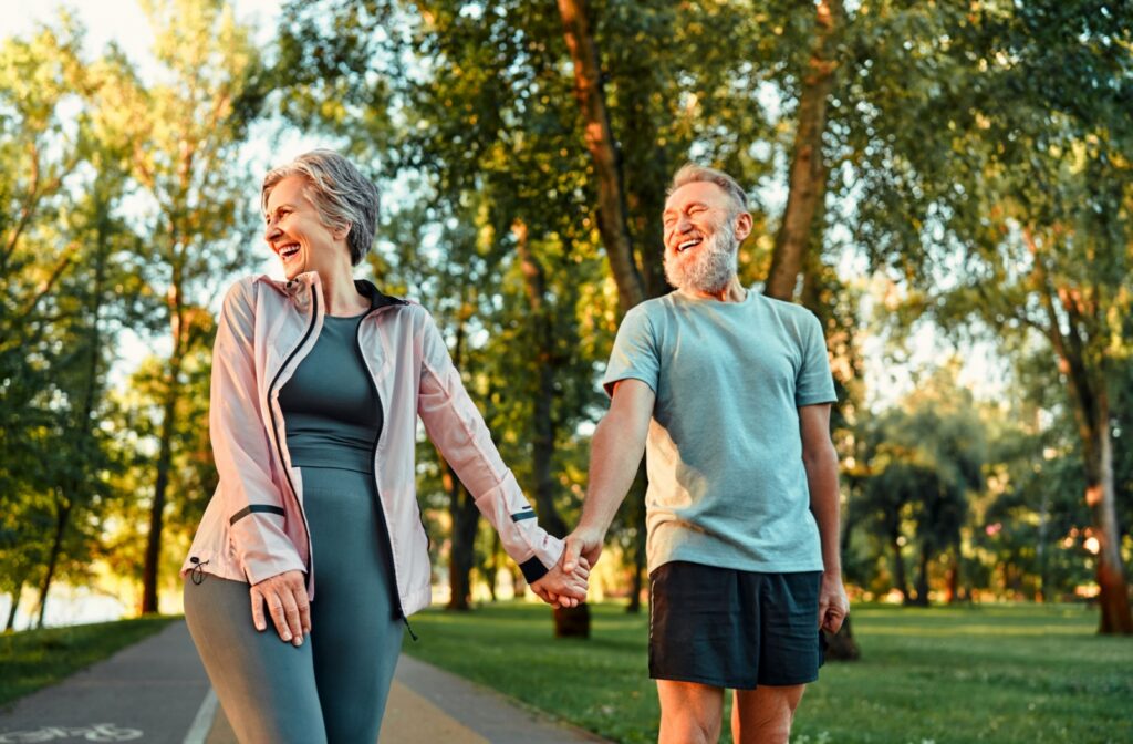 An older adult couple happily holding hands while walking in a park.